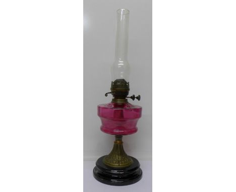 An Art Nouveau oil lamp with cranberry glass reservoir