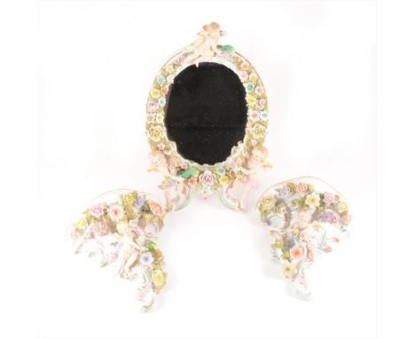 Dresden style porcelain table mirror, the frame surmounted by cherubs and with applied foliate border, oval mirror plate, woo