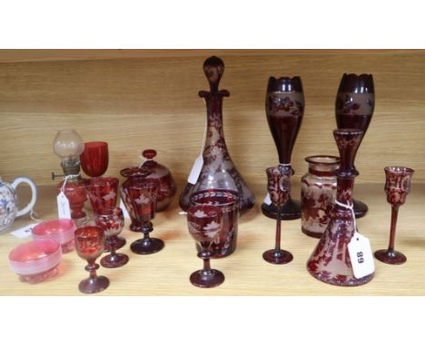 A collection of cranberry and engraved ruby glassware, including a decanter and stopper, a small carafe and stopper with two 