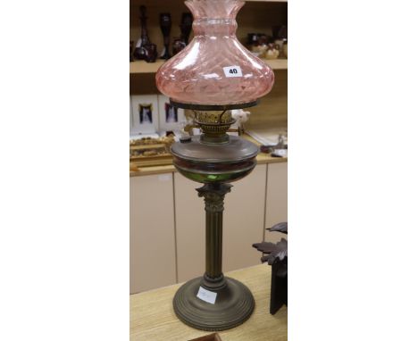 A brass oil lamp with cranberry shade height 72cm