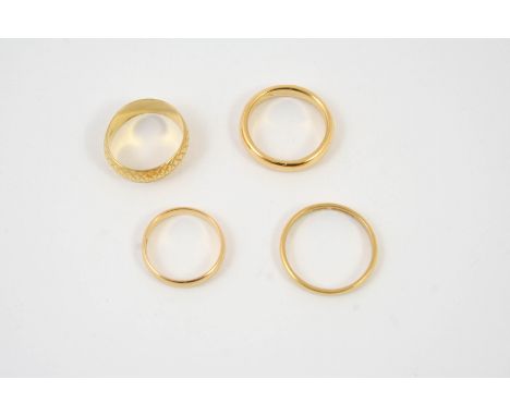 A 22CT GOLD WEDDING BAND with engraved decoration, 5.2 grams, size K 1/2, together with three plain 22ct wedding bands, 13.2 