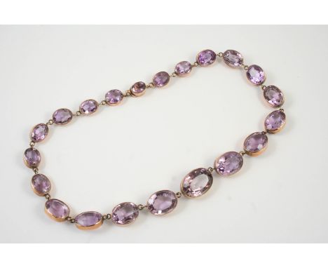 A VICTORIAN AMETHYST RIVIERE NECKLACE formed with graduated oval shaped amethysts in rose gold collet mounts, 39.5cm long