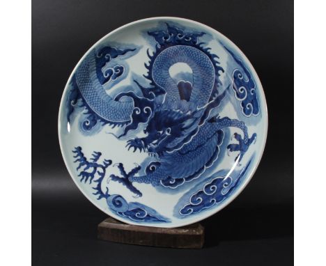 CHINESE BLUE AND WHITE CHARGER, Kangxi style but later, painted with a scrolling dragon amongst clouds, a further dragon to t