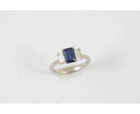 A SAPPHIRE AND DIAMOND THREE STONE RING the step-cut sapphire is set with two baguette-cut diamonds, in platinum. Size L