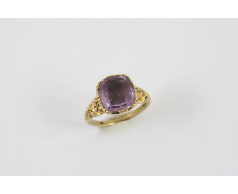 A GEORGIAN AMETHYST AND GOLD INTAGLIO RING the cushion shaped foil backed amethyst engraved with a crest, the gold mount with