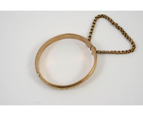 A 9CT GOLD HALF HINGED BANGLE with engraved foliate decoration, 15.7 grams
