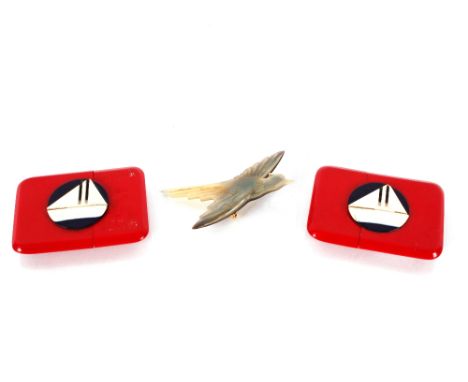 A carved horn brooch in the form of a bird; and two Art Deco buckles decorated with stylised sailing boats 