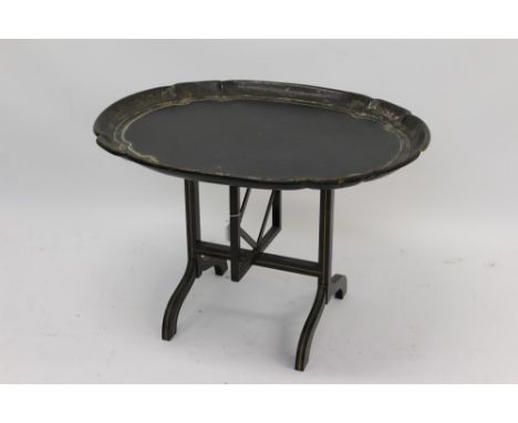 Unusual 19th century black papier mâché tray on collapsible integral stand, oval-shaped dished tray hinging on gate support a