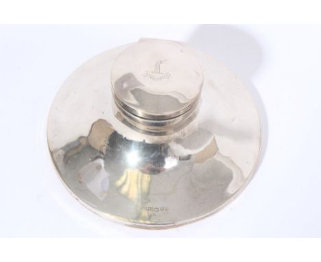 Edwardian silver capstan inkwell of circular form, with hinged domed cover and engraved armorial crest, clear glass liner and