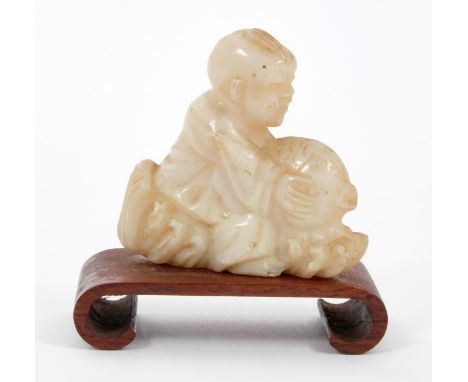 Chinese carved white jade figure of a boy, riding a carp, 4.5cm wide, raised on carved hardwood stand.Provenance: acquired in