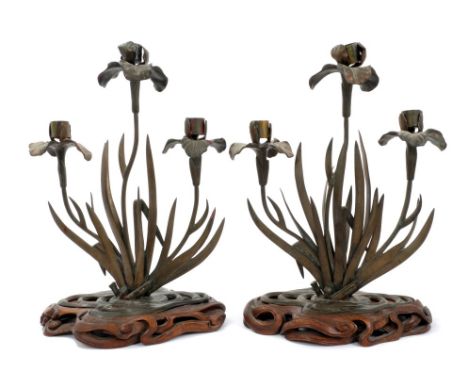 Pair of Japanese Meiji period bronzed three branch candlesticks modelled as water lilies, raised on sinuous carved hardwood b