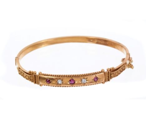 Edwardian ruby and diamond hinged bangle with three mixed cut rubies and two old cut diamonds in 9ct gold setting with applie