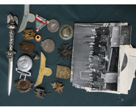 Collection of German WWII badges and insignia including a belt buckle, SS ring, eagle on Swastika pin, and ephemera relating 