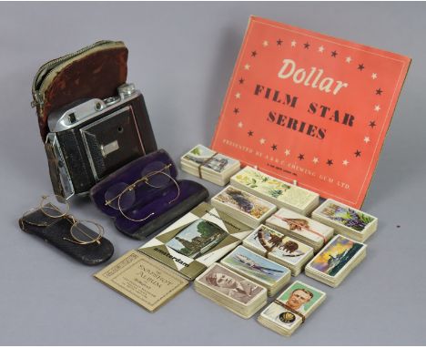 Two pairs of vintage spectacles, each cased; an Ensign folding camera; an A &amp; B. C. chewing gum picture card album “Dolla