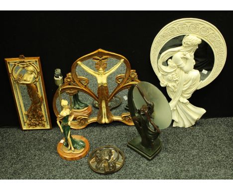 An Art Nouveau style wall mirror, decorated with a semi nude dancing girl, 48cm x 54cm; a resin Art Deco style table lamp, as