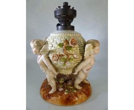 German porcelain table lamp, modelled on a flower encrusted basket supported by three cherubs, crossed swords mark in blue to