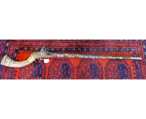 An Afghan Jezail camel gun, flint lock action, having inlaid mother of pearl decoration throughout with brass banding, a lion