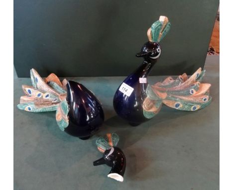 A late 20th century Goebel ceramic and blue glass model of a peacock (29cm tall), together with another (in need of repair).