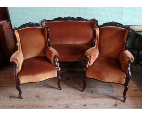 A late Victorian three piece salon suite, comprising: two seater sofa and a pair of armchairs, each upholstered on front cabr