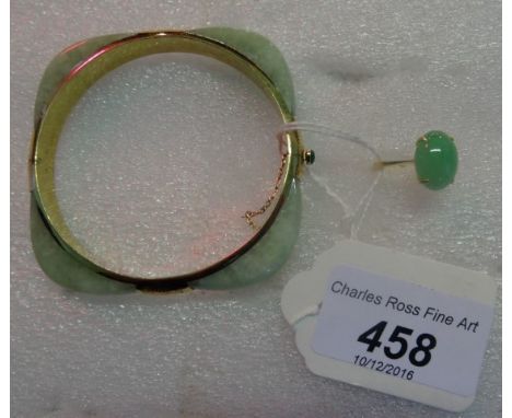 A yellow metal mounted jade bangle, the hinged bangle with partially engraved mounts and cabochon jade thumb piece to push bu