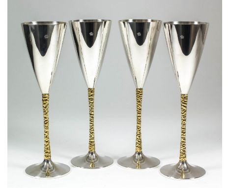 A set of four Elizabeth II silver and silver gilt champagne flutes, the plain conical bowls with textured silver gilt stems a