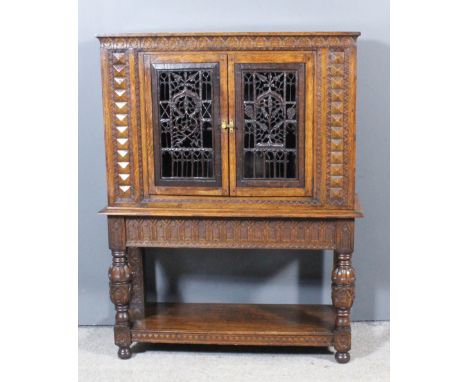 A panelled oak cupboard of "17th Century" design, fitted one shelf enclosed by a pair of carved and fretted doors, arcaded ap