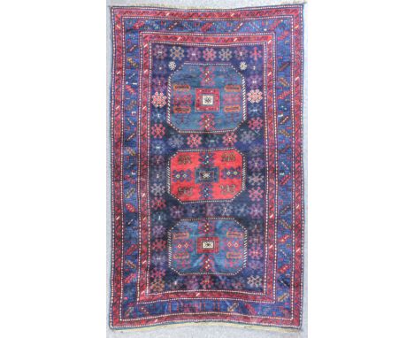 A Kazak Chaili rug woven in colour with three bold octagonal motifs filled with hooked and geometric motifs on a navy blue gr