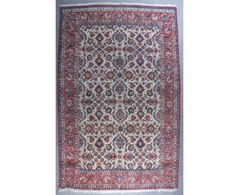 An Isfahan carpet woven in colours with a trellis of bold floral and leaf palmettes on a fawn ground, within four stripe bord