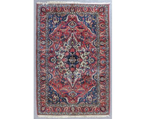 A Bakhtiari carpet woven in colours with a bold central medallion filled with stylised floral and leaf ornament and conformin