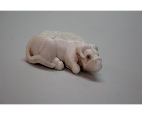 A Japanese carved ivory netsuke of a recumbent ox, Meiji period, carved with halter over back and with inset eyes, 5.1cm long