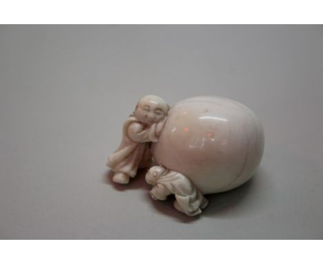 A Japanese carved ivory netsuke of two figures with a large persimmon, Meiji period, signed, 3.8cm wide.Provenance: these roo