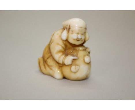 A Japanese carved ivory netsuke of a lady guarding a large sack or money bag, Meiji period, 4cm high.