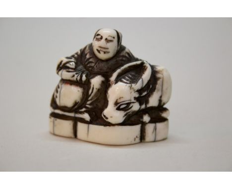 A Japanese carved ivory netsuke of a man with an ox, Meiji period, 3.8cm wide.