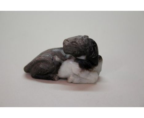 A Japanese carved amber netsuke of a warty fish or three legged toad, 3.4cm wide; together with a carved jade figure of a rec