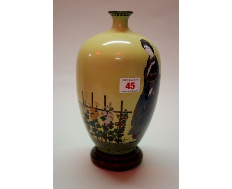 A Japanese cloisonne enamel vase, decorated with a lady in a flower garden against a pale yellow ground, 24.5cm high, on wood