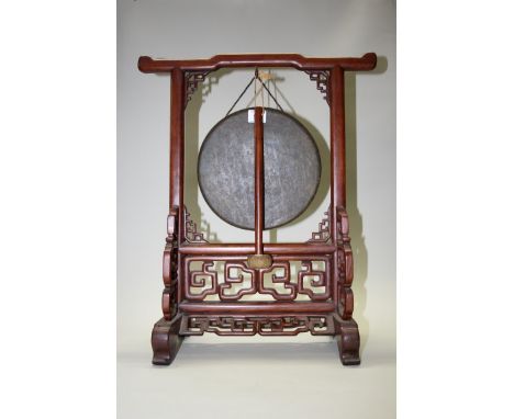 A Chinese carved and pierced hardwood gong stand, early 20th century, with original bronze gong and beater, the stand 52.5cm 
