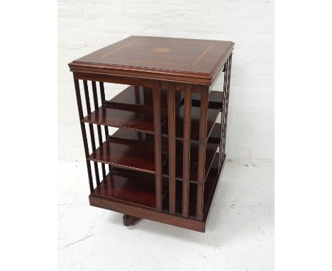 EDWARDIAN MAHOGANY AND INLAID REVOLVING BOOKCASEwith a square moulded top above four open and part slatted shelf sides, stand