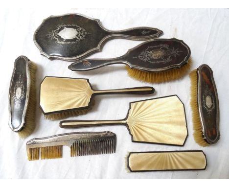 GEORGE V DRESSING TABLE SET with cream enamel and silver decoration, comprising a hand mirror and two brushes, Birmingham 193