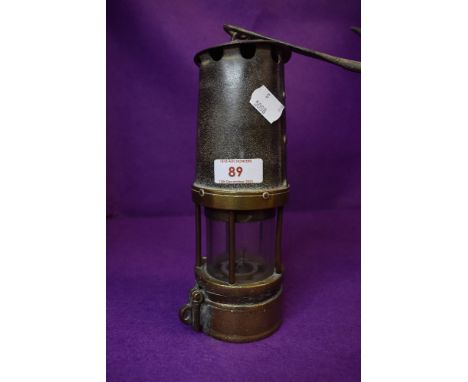 A vintage coal miners safety lamp with a brass and cast shell