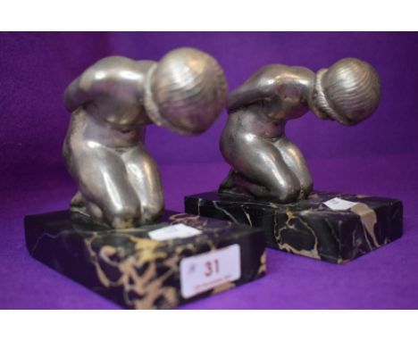 A pair of art deco book ends on marble bases of two nude kneeling ladies