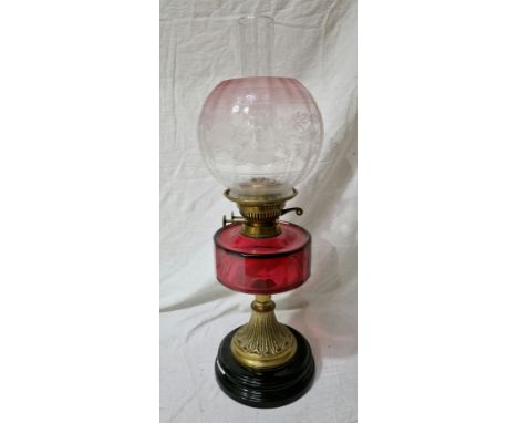 A brass oil lamp with cranberry glass reservoir and etched cranberry tinted glass shade.Condition:- General wear through age 