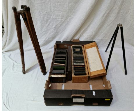 Two boxes of glass slides including hand coloured, travel, historical, German etc together with two vintage tripods.  