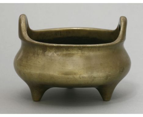 A bronze incense burner, 20th century, the compressed body with two pierced log handles, on three feet, polished patina, cast