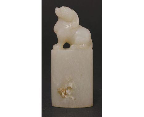 An uncut jade Seal, 20th century, the clear white, pale green and bone stone of oval section below a mythical beast with long