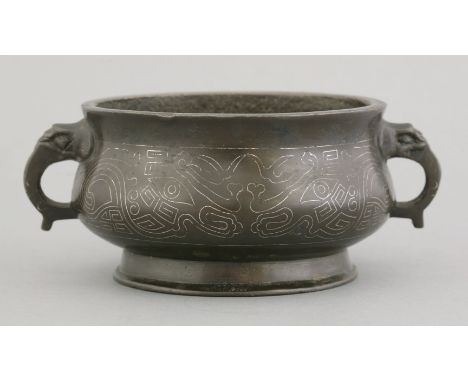 An inlaid bronze Censer, early Qing dynasty, the squat body with archaic silver-wired taotie masks on a raised foot, the side