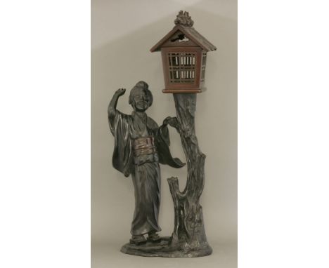 A bronze Table Lamp, c.1900, with a smiling bijin standing beside a gnarled tree trunk, on which rests a patinated birdhouse 