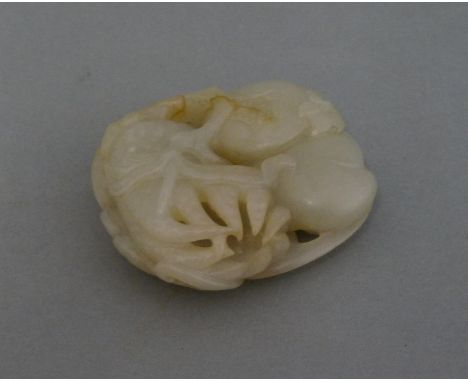 A jade Group, second half of 20th century, carved with three bats above a peach, a pomegranate and a finger citron, 5.8cm
