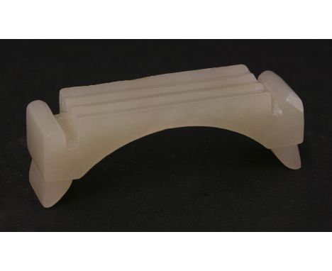 A jade ink stick rest, 20th century, the flat top cut with three channels above an arched foot, 7.8cm