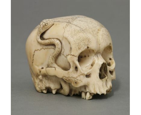 A Japanese ivory Memento Mori, c.1880, carved in the form of a skull and with a snake slithering over it, the details careful