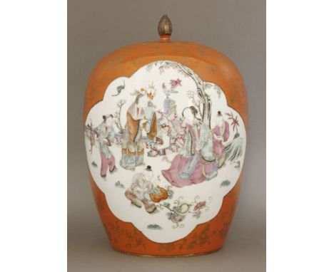 A famille rose, coral-ground Jar and Cover, c.1920, painted with a couple appraising precious objects with three boy attendan